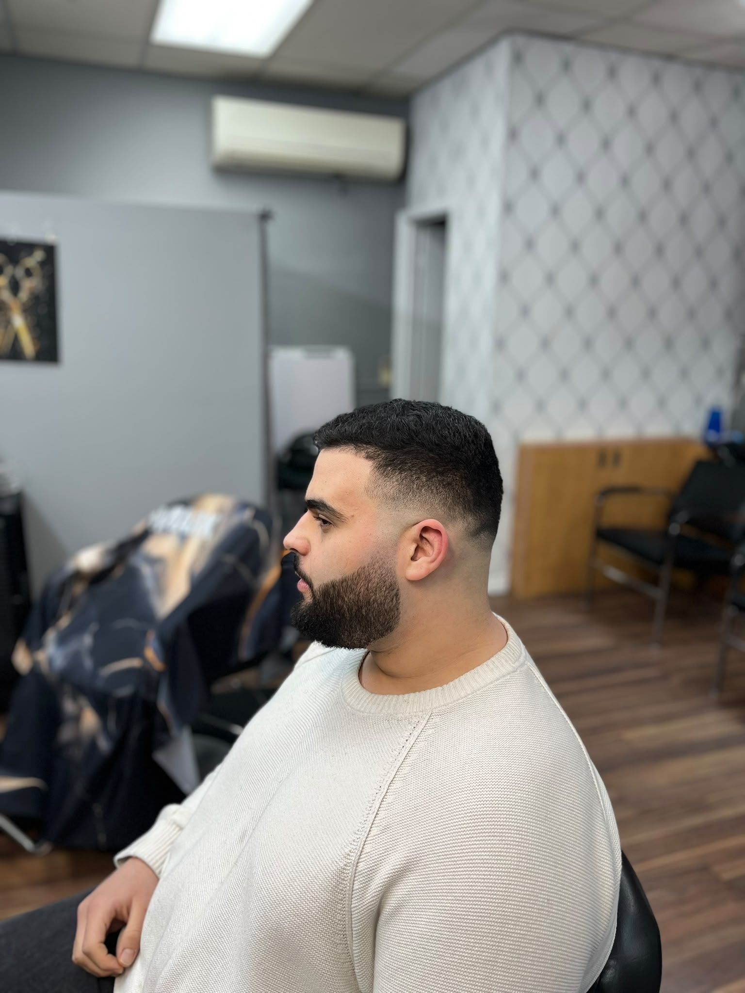 Skin fade with a textured top and a sculpted full beard