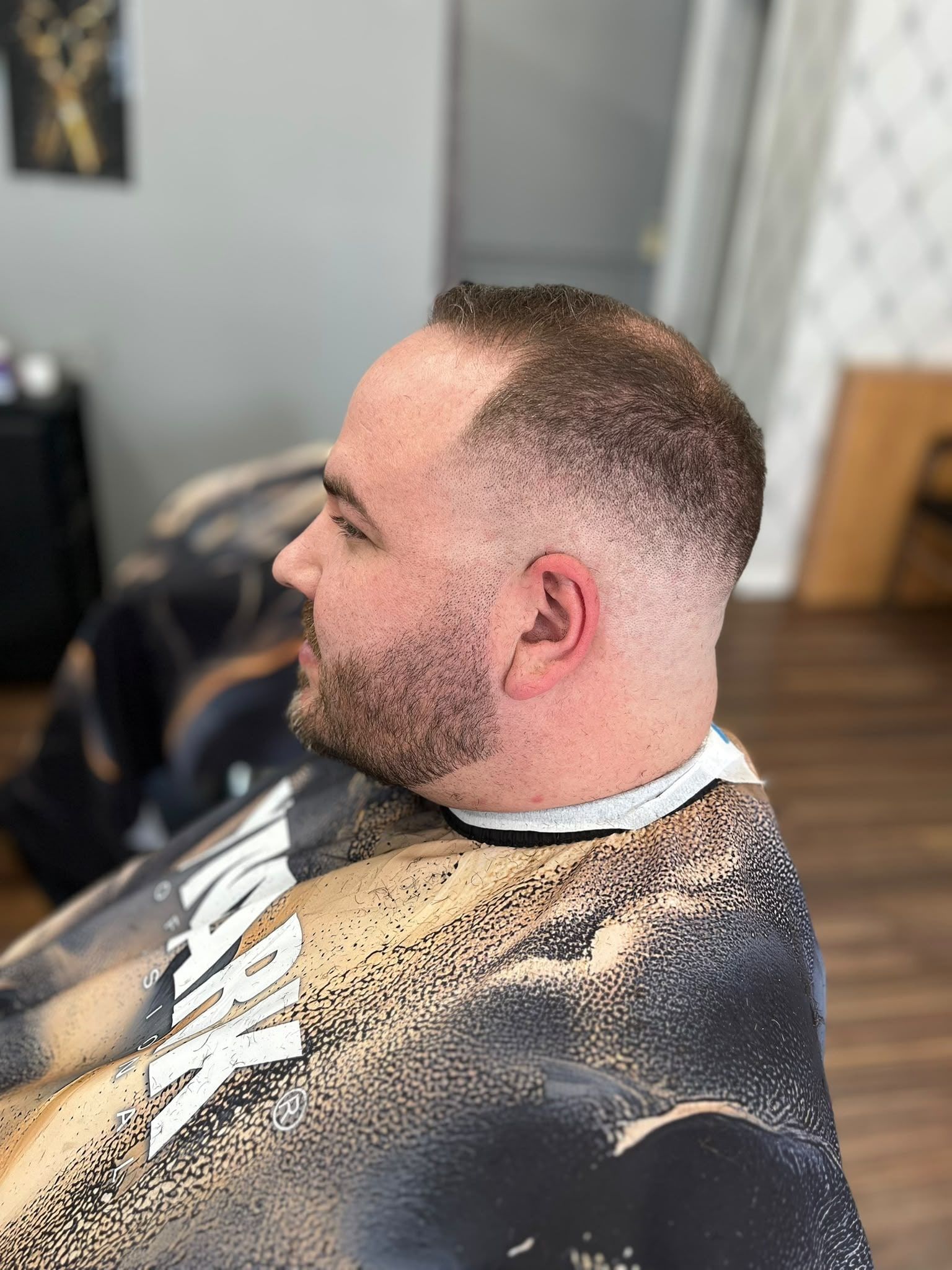 Short buzzed top with a skin fade blended into the beard
