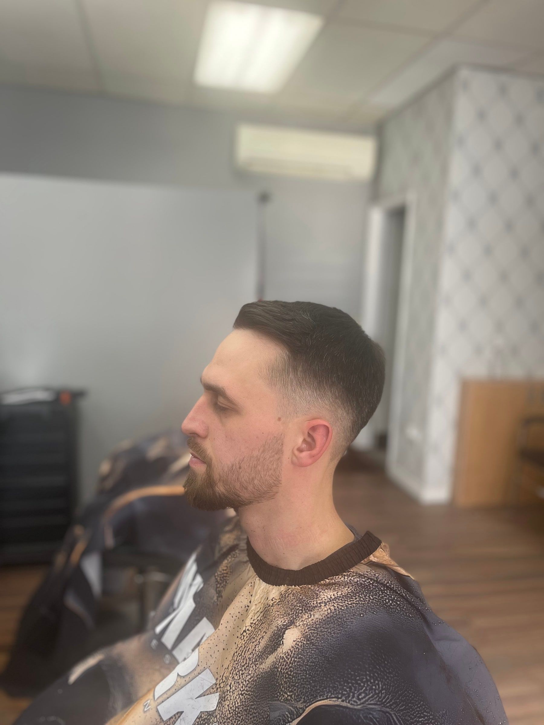 Low taper with a side part and a short beard